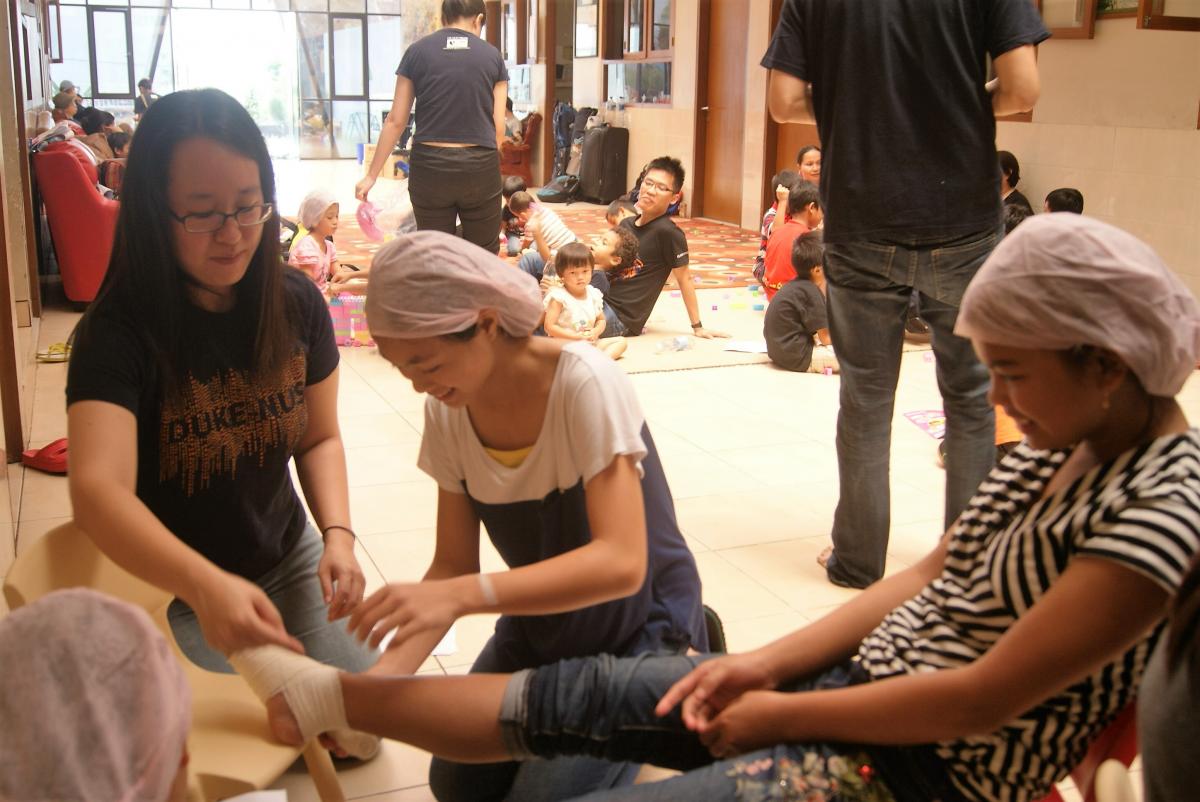 Joanne Ting (MS1) guiding a teenager at the orphanage as she practices bandaging for an ankle sprain