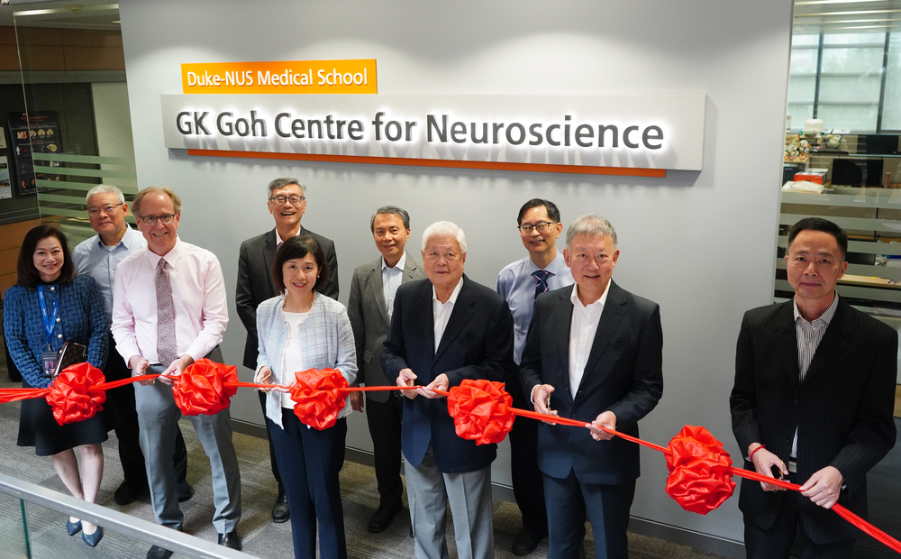 A group of people are cutting a ribbon in front of the signage of a newly launched research centre for neuroscience