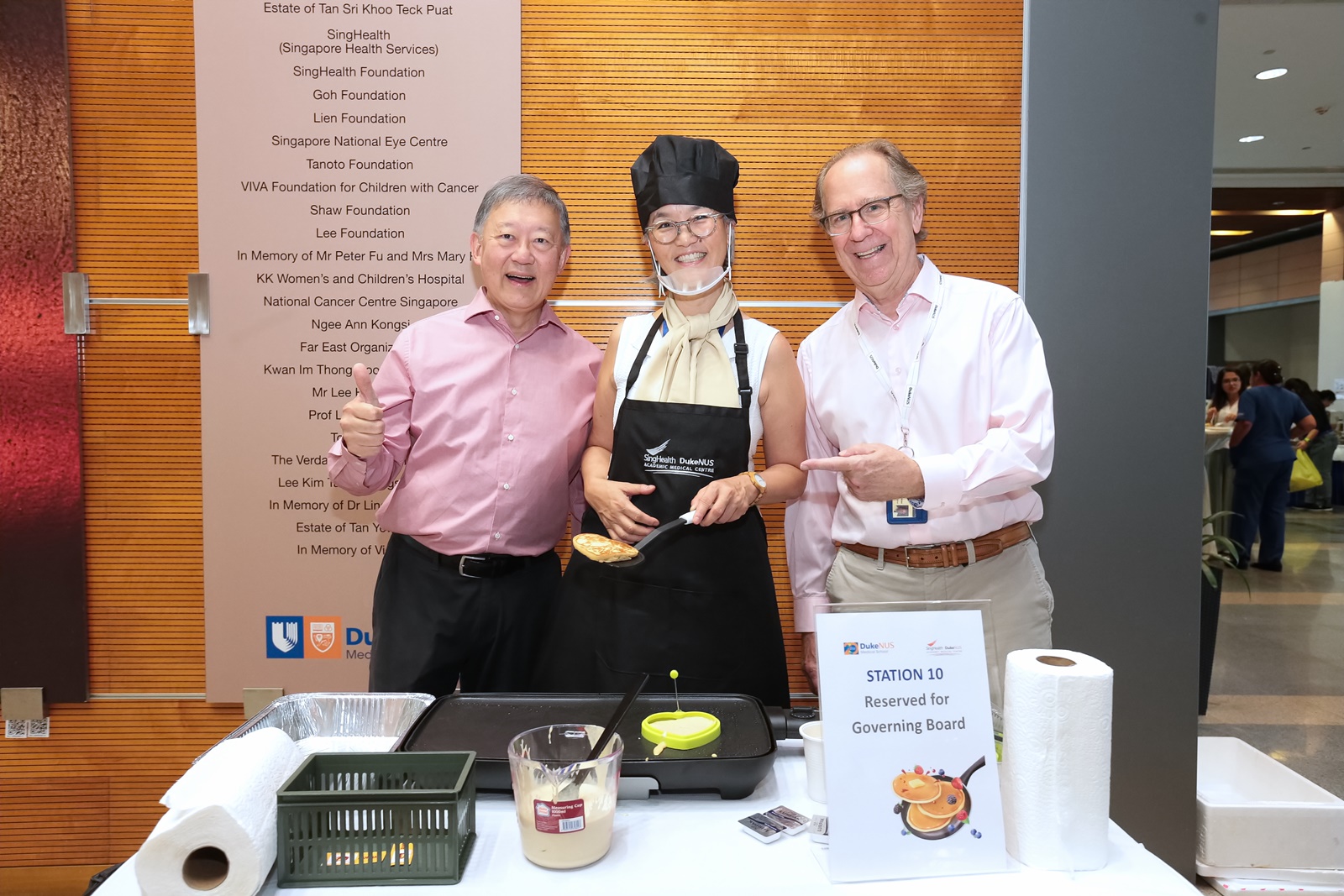 From left to right: Duke-NUS Governing Board members Mr Goh Yew Lin and Ms Marie Elaine Teo, with Dean Tom Coffman, preparing for hungry pancake eaters.