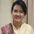 Maya Gustina Andarini in a yellow traditional indonesian attire with a red scarf across her right shoulder